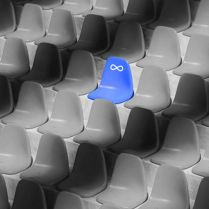 A single blue chair stands out among rows of uniform gray seats on a concrete base, with a white infinity symbol displayed on its backrest. The image visually reinforces the accompanying post by highlighting one distinctive seat among many, matching the "Your seat's been waiting" message with the Meta infinity logo prominently featured.