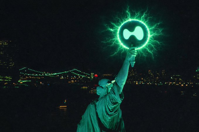 A figure draped in robes stands against a nighttime city skyline, holding aloft a glowing green orb resembling the Hyperliquid (HYPE) logo with electric tendrils radiating outward, symbolizing energy and connection. The image visually reinforces the post's call to connect within the Hyperliquid community by depicting a powerful, beacon-like embodiment of the brand.