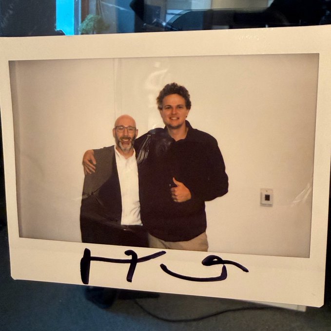A polaroid photo of two men posing together with arms around each other, featuring handwritten text "HKG" at the bottom. The image accompanies a post announcing a podcast recording with Hyperliquid, with the "HKG" likely referring to the podcast's name or abbreviation.