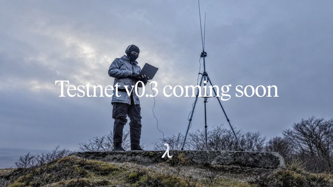 A person in camouflage gear and a hood stands on a grassy hill holding a laptop next to a tripod with antennas, with overlay text reading 'Testnet v0.3 coming soon' and a lambda symbol.