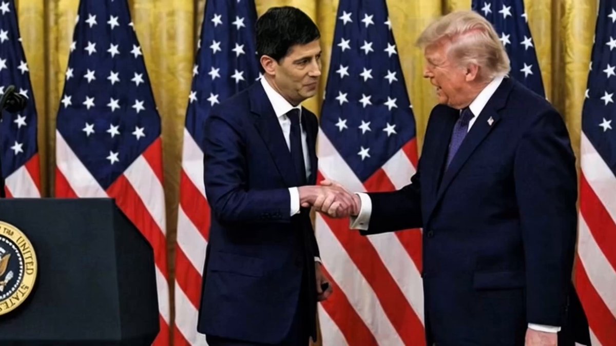 The image shows two men shaking hands, one wearing a suit and the other dressed in a blue suit with an American flag behind them. The background features several American flags, suggesting that they are in a room or event related to U.S. politics or government. The text on the image reads "RUMOR ALERT Rumors claim the U.S. Federal Reserve could explore XRP as part of a future strategy to improve debt management efficiency." This implies that there might be some speculation or rumor about the Federal Reserve considering using cryptocurrency like XRP for their financial operations, but nothing is confirmed in the image itself.