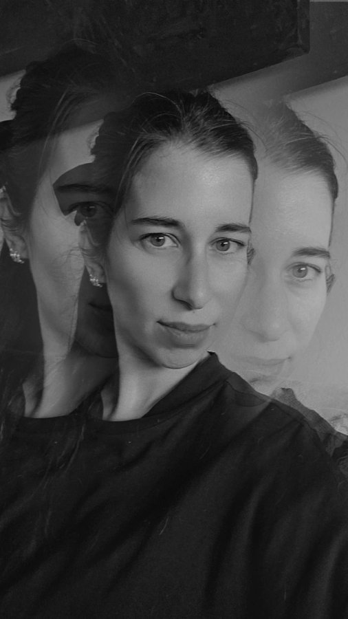 A black and white photo featuring a young woman with her hair pulled back, shown with a double exposure or mirrored ghosting effect.