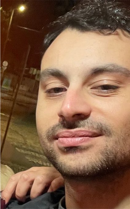 A close-up selfie of a man with dark hair and stubble, looking slightly skeptical or unimpressed. His expression mirrors the post's caption, humorously personifying how memecoins "look at him lately" with a mix of curiosity and judgment.