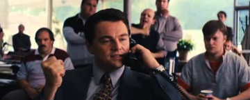 A man in a suit enthusiastically talks on a telephone with a clenched fist, surrounded by onlookers in an office setting, in a scene that resembles the iconic Wolf of Wall Street celebration. The image appears unrelated to the Shiba Inu "PONSAN" token or the PONS launchpad mentioned in the post, as no dog, text, or launchpad branding is visible.