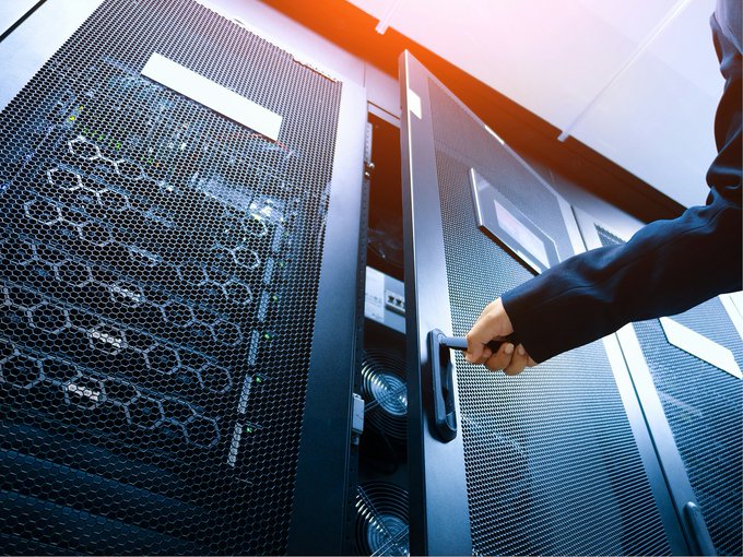 A hand opens a server rack door in a data center, symbolizing the underlying blockchain infrastructure that enables tokenized finance—where, despite a vast ecosystem of 7,000+ tokenized products spanning 12 asset classes, $32.9 billion sits inactive without weekly transfer activity, highlighting the concentration of liquidity in only a handful of tokens.