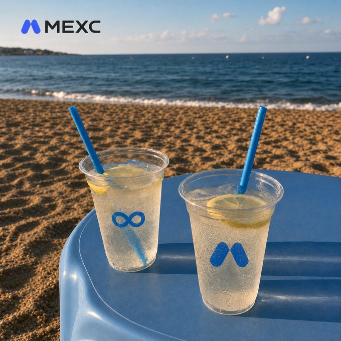 Two clear plastic cups filled with lemonade (each garnished with a lemon slice and a blue straw) sit on a blue beach chair overlooking the sandy shore and sea. The cups display MEXC's logo design, with one featuring the infinity-style symbol and the other the signature "M" mark, reinforcing the brand's presence in this summery, vacation-themed scene.