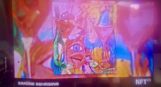 A digital screen displaying an NFT artwork titled 'SIMONE BEHRSING' featuring colorful abstract wine glasses and a stylized face in vibrant rainbow hues, marked with 'NFT PRO' logo.