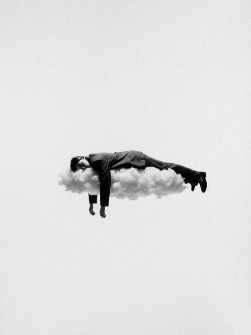 A surreal black-and-white composite image showing a man in a suit lying horizontally on a small cloud against a plain background.