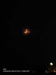 A dark nighttime photograph showing a faint orange glow in the sky, possibly a rocket launch, with a small timestamp visible at the bottom left.