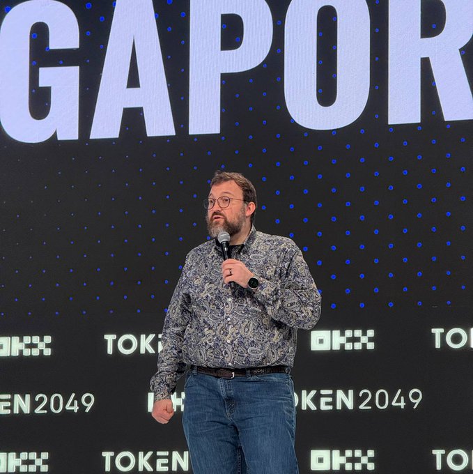 Charles Hoskinson speaks at TOKEN2049 (with "GAPOR" and "TOKEN2049" branding visible), addressing attendees with a microphone as he advocates for the "Night Frame" as a smarter successor to traditional smart contracts, integrating zero-knowledge proofs, MPC, and trusted execution environments on Midnight.