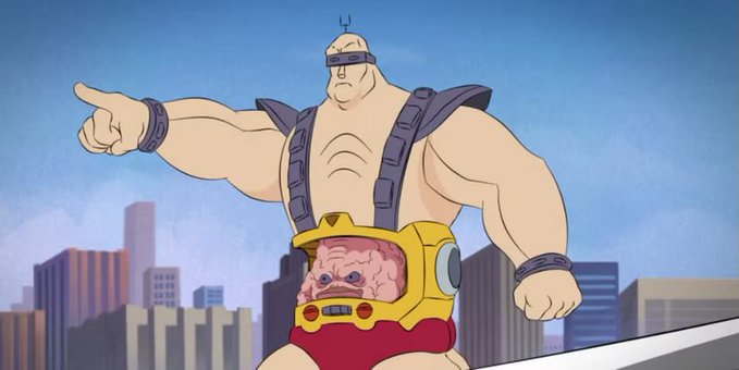 An animated cartoon character resembling Krang from Teenage Mutant Ninja Turtles, a muscular bald figure with a small brain-like creature in a transparent mechanical stomach piece, pointing dramatically against a city skyline background.