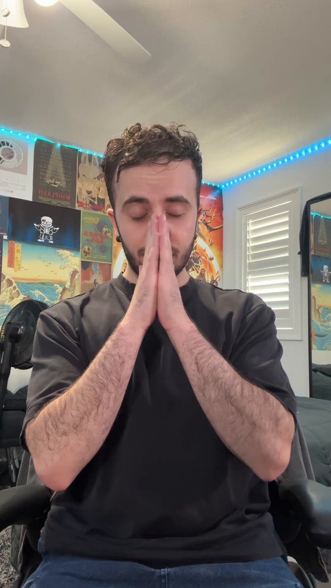 The image features a man sitting with his hands clasped together while wearing a black shirt, inside a room that resembles an office or home setting. The walls are adorned with colorful posters and paintings. On one of these walls, there's a post celebrating someone for their achievements, which appears to be worth at least $67 in the caption.