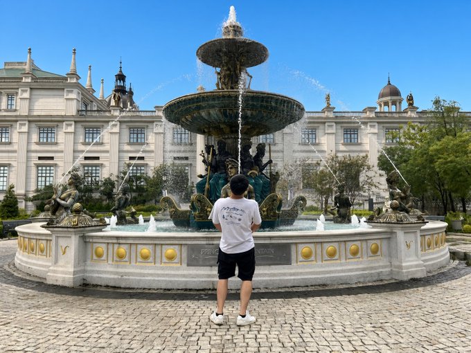 A person stands before an ornate fountain labeled "PRO..." spraying water high into the air in front of a grand European-style building, humorously posing as if their "firepower" matches the fountain's spray in the accompanying crypto post referencing TermMaxFi token price.
