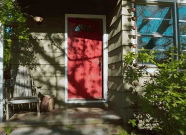The image shows a red door with white trim, located outside of a house. There are two benches visible in front of the door - one wooden bench and another made of wood. The scene also includes trees and bushes surrounding the area. A post on social media has been shared about the crypto recovery, which is titled "gm. Will the crypto recovery last? Are you hyped today?".