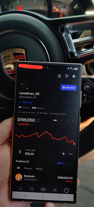 A smartphone held in front of a Porsche steering wheel displays a trading app showing a portfolio for 'Leviathan_39' with a position in 'Buttcoin' worth $166,524.89, down 6.67%.