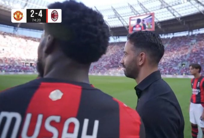 A still from a soccer match showing a coach looking at a player with 'MUSOL' on his red and black jersey, with a scoreboard reading '2-4' at 74:20 between Manchester United and AC Milan.
