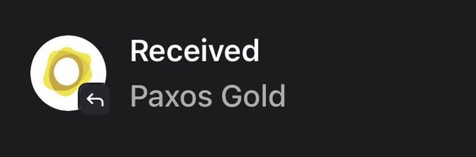 A digital notification screen on a dark background showing a gold coin icon with the text 'Received Paxos Gold.'