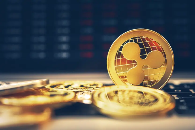 A physical XRP (Ripple) cryptocurrency coin stands upright on a stack of gold coins against a blurred background of financial charts, symbolizing the coin's potential rise and decoupling from Bitcoin as part of the new financial system.