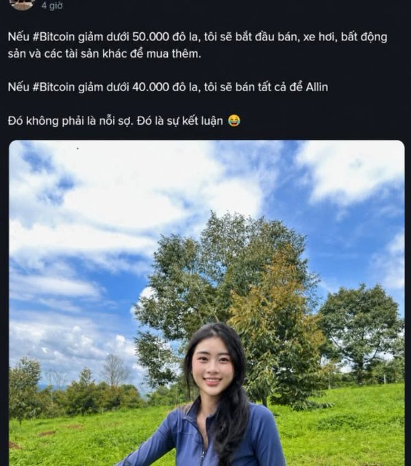 A young woman in a blue shirt smiles in a sunny, grassy field with trees and a bright blue sky behind her, while the post above declares intentions to sell cars, real estate, and other assets to buy more Bitcoin if it drops under $50,000, and to go "all in" if it falls below $40,000—framed not as fear but as a firm decision.