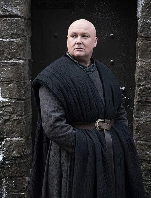 A bald, heavyset man in a long black robe and belt stands solemnly in a stone doorway, evoking the austere imagery of a medieval lord or "Lord Varys"-type figure. The post's joke about someone missing a market-moving call fits the image's serious, judgmental demeanor—as if this imposing figure is silently disapproving of the trader who faded the call before a 60bps move.
