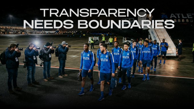 A men's sports team wearing blue "ATLETA" tracksuits walks across an airfield at night, surrounded by photographers with cameras, beneath the headline "TRANSPARENCY NEEDS BOUNDARIES." The image illustrates the post's message that real transparency in sports isn't about making everything publicly visible—here, athletes and operations are exposed to media scrutiny—but about ensuring the *right* information is trustworthy and verifiable.