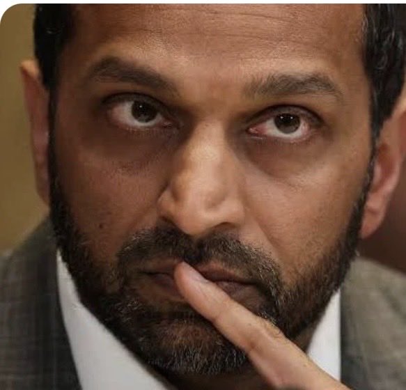 A bearded man in a suit holds his finger to his chin in a contemplative pose, visually echoing the post's call for scrutiny over Kash Patel's alleged failure to disclose $100,001–$500,000 in MicroStrategy (MSTR) stock holdings within the required 45-day window, given the company's significant Bitcoin investments and DOJ contracts.