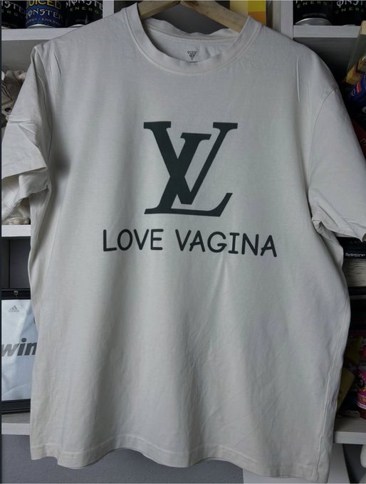 A white t-shirt hangs on display, featuring a black interlocking 'LV' monogram logo above the text 'LOVE VAGINA'.