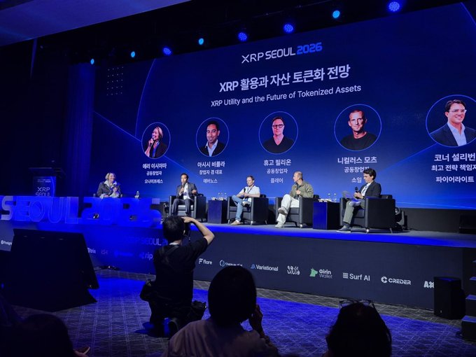 A panel discussion at the XRP SEOUL 2025 conference, featuring speakers under the title 'XRP 활용과 자산 토큰화 전망 / XRP Utility and the Future of Tokenized Assets', with an audience member photographing the event.