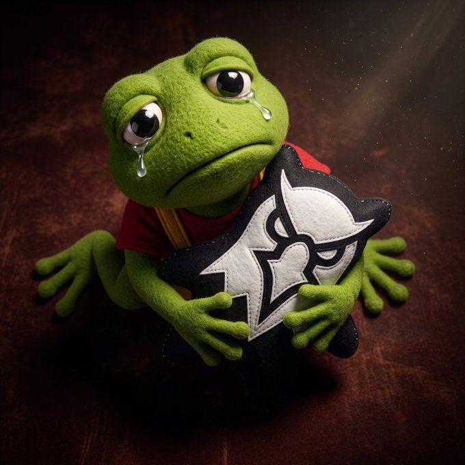 A 3D-rendered green frog wearing a red shirt sits against a dark background, shedding tears while clutching a black and white shield-shaped pillow.