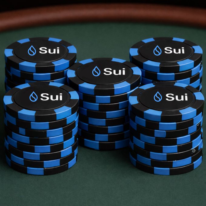 Multiple stacks of blue and black poker-style chips branded with the 'Sui' cryptocurrency logo, arranged on a green felt casino table.