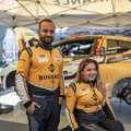 A man and young girl wearing matching yellow SHARP (auto glass) shirts posing together in a garage setting with vehicles in the background.