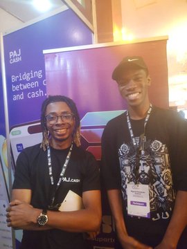 Two men pose together at what appears to be the "Unchain Summer" event hosted by NFT__NG, with a "PAJ CASH" banner promoting "Bridging between c[rypto] and cash" visible in the background. The man on the right wears a lanyard with an event badge, and the caption highlights their reunion after a year, celebrating the author's growth from winning 1 to 29 bounties on SuperteamEarn.