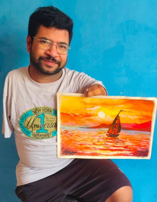 The image features a man sitting down with his arm raised up holding an artwork of a sailboat against a blue background. The artwork depicts a beautiful sunset over water, creating a serene atmosphere. The man appears to be posing for the picture while showcasing the painting he is holding. The caption at the bottom of the image reads "If you're into NFTs and ARTs, I love you." This suggests that the man might have an interest in art or digital assets related to paintings or other creative works.
