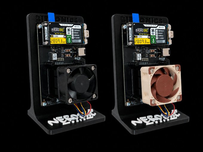 Two NerdMiner Bitcoin Solo mining devices on stands against a black background, each with a small LCD screen displaying 'NerdMiner v1.6.2' and a hash rate of 2809.3, one with a black fan and the other with a brown fan.