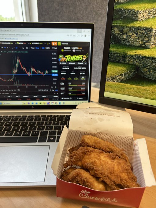 A box of Chick-fil-A chicken tenders sits on a desk in front of a laptop displaying a TradingView chart for the $TENDIES meme token, humorously illustrating the "Day 16" campaign to flip the token's price to match the cost of a chicken tender.