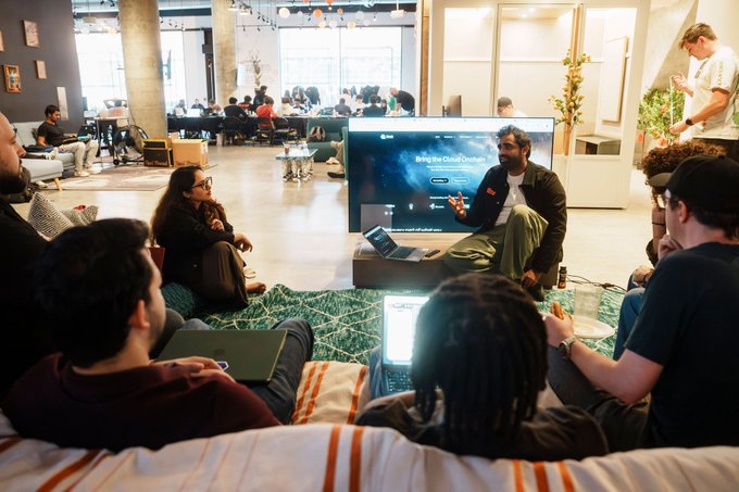 A group of people sit on cushions watching a presentation about 'Bring the Dead Ocean' in a modern co-working space.