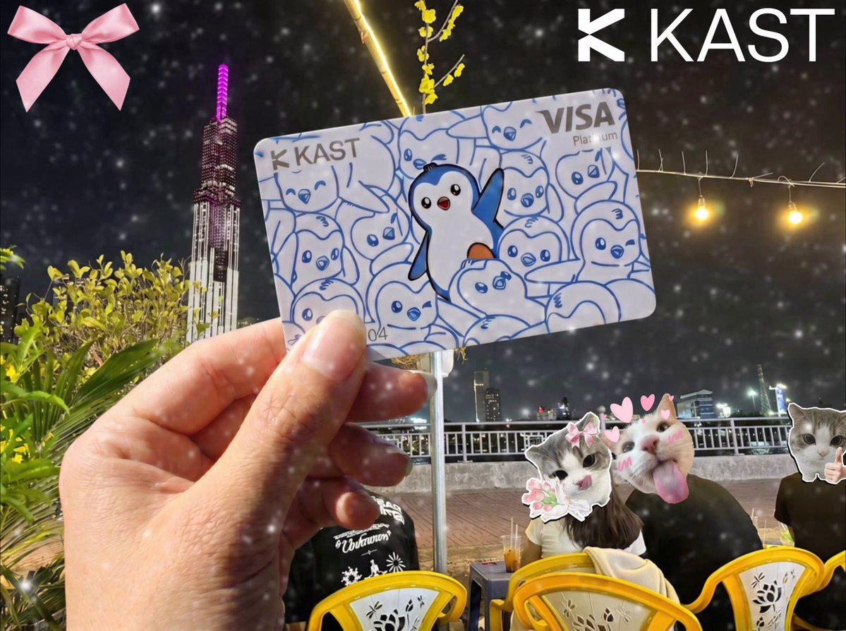 The image features a hand holding up a Visa card with a penguin design on it. The card has the words "gKAST" written on it, indicating that this is an Instagram post from someone named @KASTxyz who is enjoying their time in Ho Chi Minh City, Vietnam. The background of the photo shows a cityscape at night, complete with lights and buildings, creating a vibrant atmosphere for capturing memorable moments.