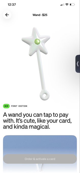 The image shows a cell phone screen with an app called "Wand-25" displayed, which appears to be for purchasing a wand. The text on the screen reads, "A wand you can tap to pay. With, its cute, like your card, and kinda magical." This suggests that the user might be interested in buying a wand as a gift or for personal use.