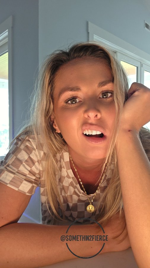 A blonde woman rests her head on her hand, looking directly at the viewer with her mouth slightly open, wearing a brown checkered top and a gold pendant necklace. The image is watermarked "@somethin2fierce" at the bottom, and the post references "$XRP," suggesting the image is used to convey an emotional reaction—likely surprise or exhaustion—to the recent volatility of XRP.