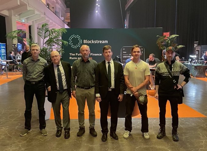 Six men pose together at the BTC Helsinki 2026 conference in front of a Blockstream booth displaying the slogan "The Future of Finance Runs on Bitcoin," with the image capturing the group mentioned in the post, likely including Bitcoin influencers and industry figures like Adam Back and Martti Malmi.