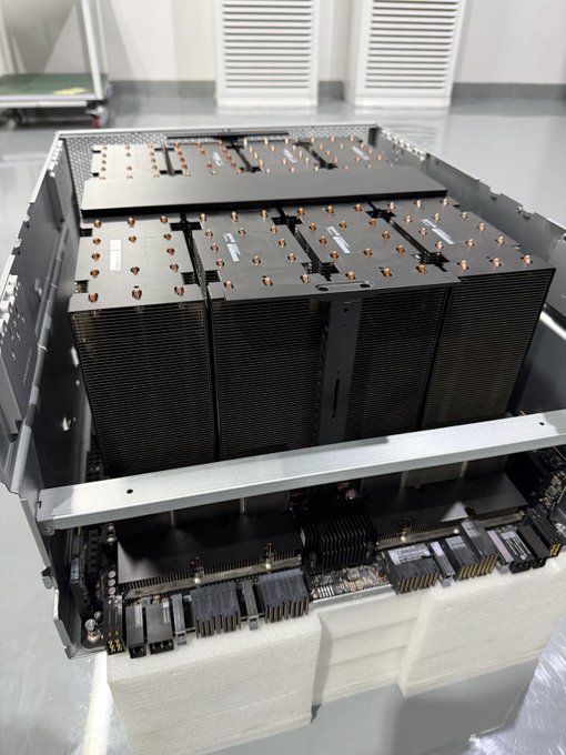 A large computer server or mining rig chassis with multiple heat sinks and copper heat pipes visible inside, resting on foam padding.