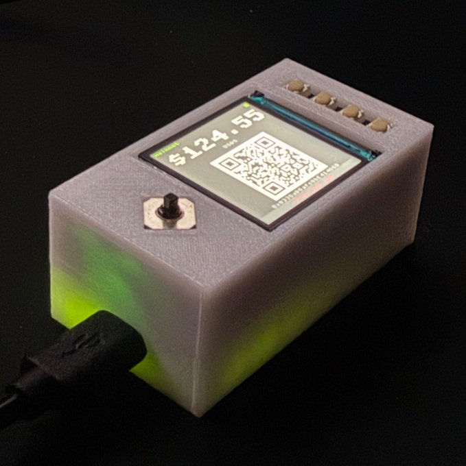 A 3D-printed DIY hardware crypto wallet displaying "$124.55" and a QR code for transactions, with a USB cable plugged in and green LED lighting visible through the casing, reflecting the post's excitement about building a customizable, open-source cold storage device.