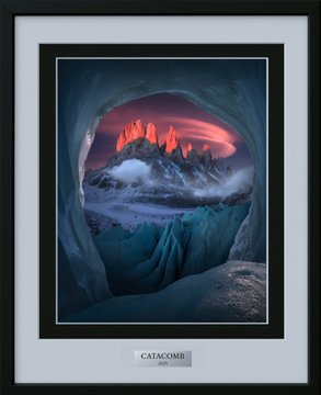 The image features a framed picture of Catacomb, an arch with rock formations, taken from inside one of the openings within a snow cave or ice cave. The print showcases the stunning scenery around the arch, providing a close-up view that highlights the intricate details and textures present in the icy landscape. It appears to be an impressive piece of photography capturing the essence of this rare 1/1 physical print.