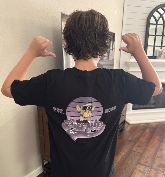 A photo of a person wearing a black t-shirt featuring a cartoon monkey graphic with sunglasses and the text 'EST. 2018 Purple Ape' on the back.