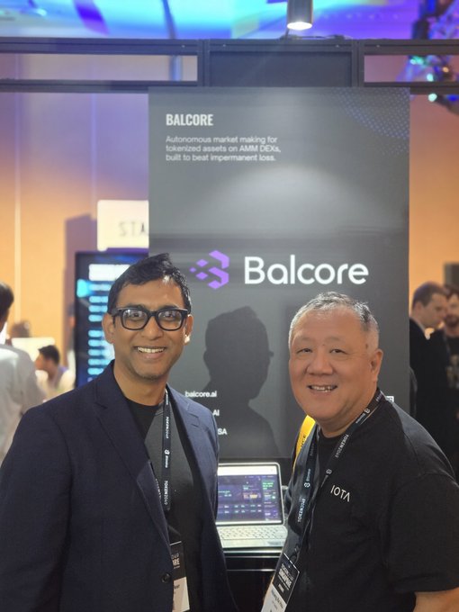 Two men smile for a photo at a conference booth displaying 'BALCORE - Autonomous market making for tokenized assets on AMM DEXal, built to beat impermanent loss' with the Balcore logo.