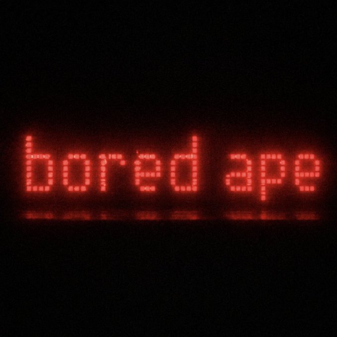 A glowing red LED sign displays the text "bored ape" against a dark background, directly referencing the popular Bored Ape Yacht Club NFT collection referenced in the post's call-and-response prompt.