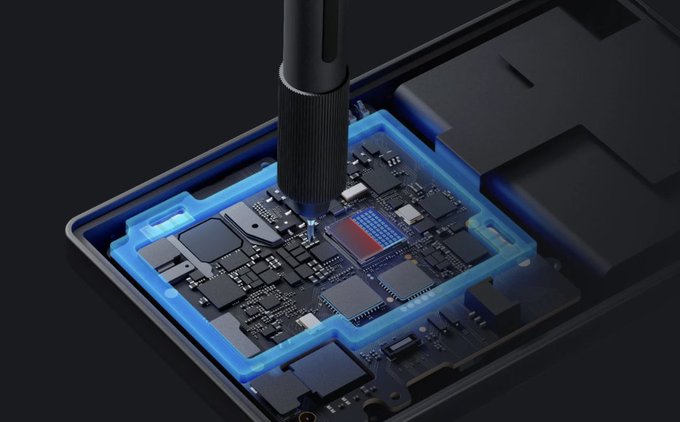 A close-up of a screwdriver working on an exposed smartphone circuit board with blue glowing accents highlighting specific components.