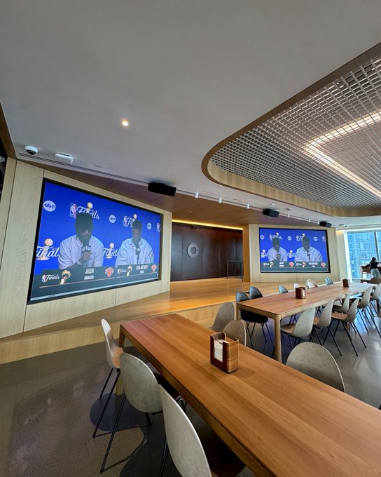 The image shows a large room with two TVs mounted on the walls, one of which displays a sports game. There are several chairs arranged around dining tables, suggesting that this space could be used for both watching television and enjoying meals together. The focus of the image is on the TV screens and the arrangement of the furniture in the room, indicating it might be a place where people gather to watch sports events or engage in conversations while having their meals.

The post "Game 4 ready" suggests that there could be an upcoming event or competition related to the sport being displayed on one of the TVs. This implies that the room may have been prepared for this occasion, with seating arrangements and possibly additional tables set up for guests attending the event.