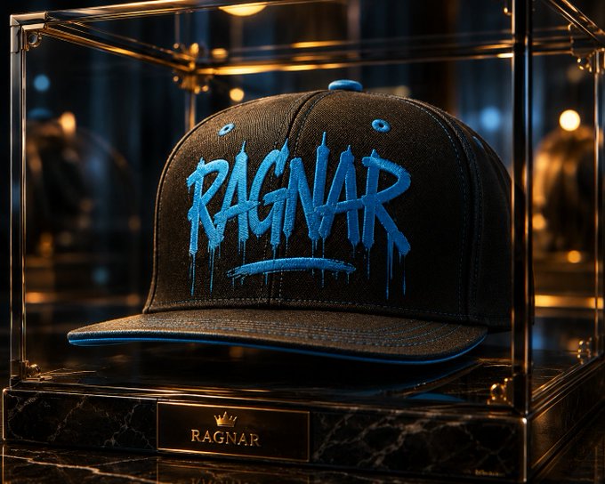 A stylized image of a black and blue baseball cap with 'RAGNAR' written in dripping blue graffiti-style text, displayed inside a glass display case with a marble base featuring a gold 'RAGNAR' nameplate.