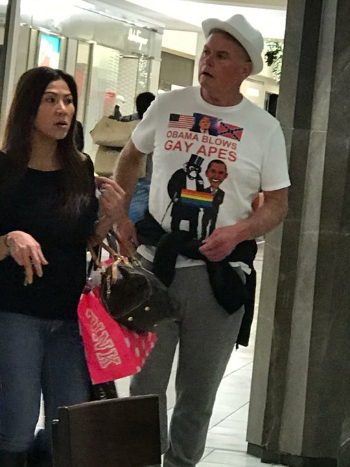 The image shows a woman helping a man in a wheelchair navigate through a doorway; the man is wearing a white hat and an offensive t-shirt depicting Barack and Michelle Obama with the text "OBAMA BLOWS GAY APES." The "Pond0x.com" reference appears to be associated with the meme-style commentary on the political apparel shown in the photo.